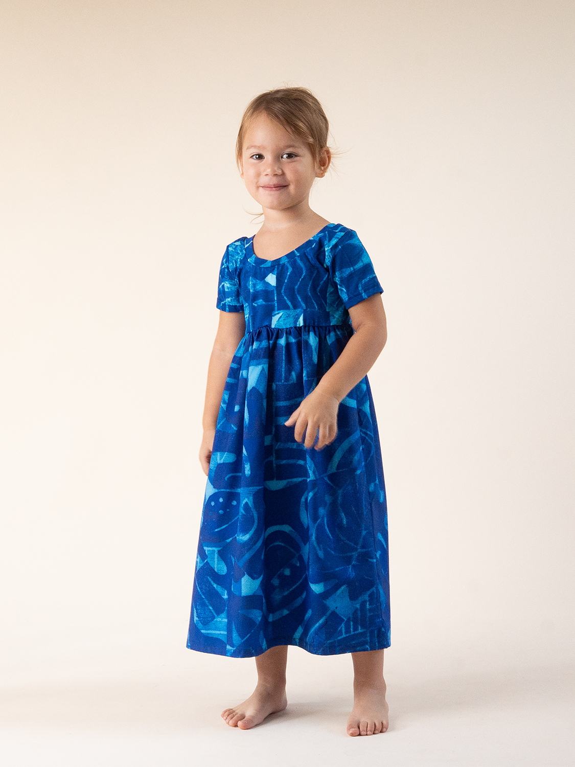 Child wearing a blue dress with a pattern on a white background